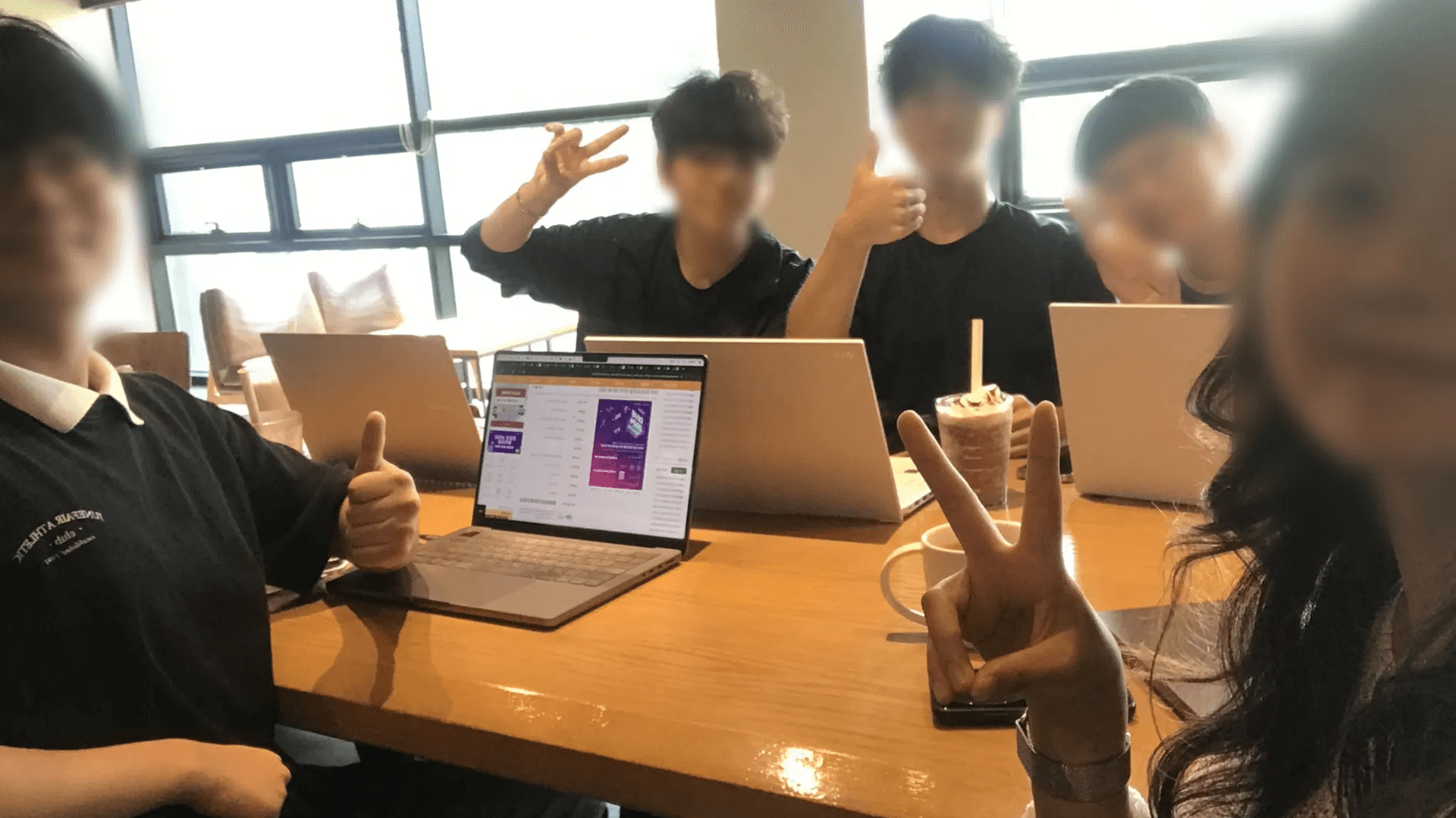 바운더리 팀원들이 카페에서 노트북을 펼쳐 두고 손가락 브이를 하며 찍은 단체 사진